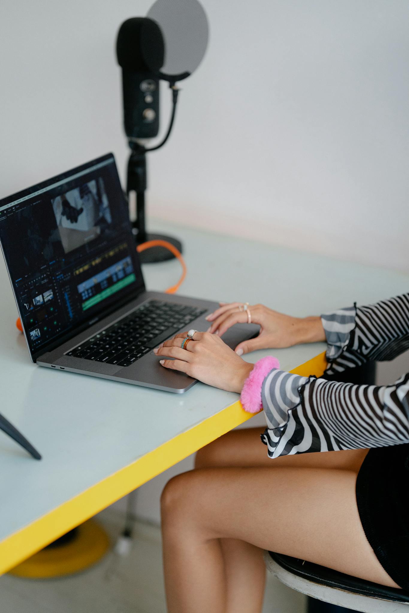 Young woman using laptop for video editing in a modern workspace.